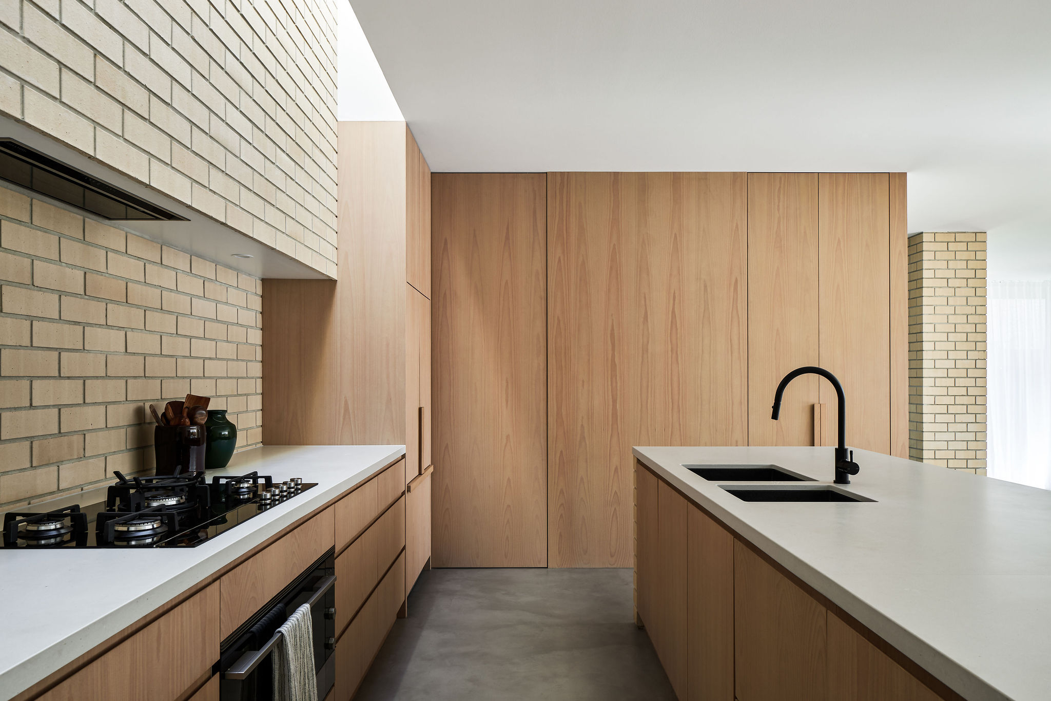 Modern architect designed kitchen with skylight, oak veneer cabinets, white stone benchtops, black sinks and taps