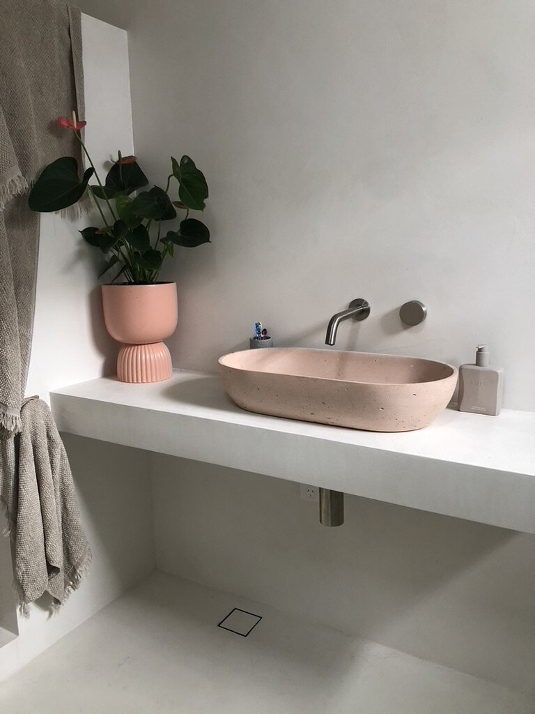 Modern architect designed bathroom renovation with pale microcement walls and benchtop, pink above counter basin
