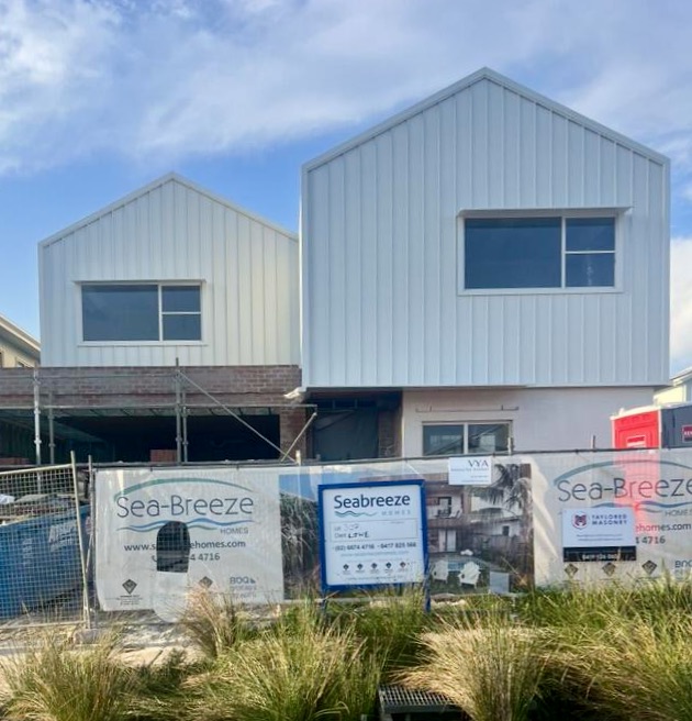 Modern architect designed house under construction with white ribbed metal wall cladding, Heka Hoods over aluminium windows