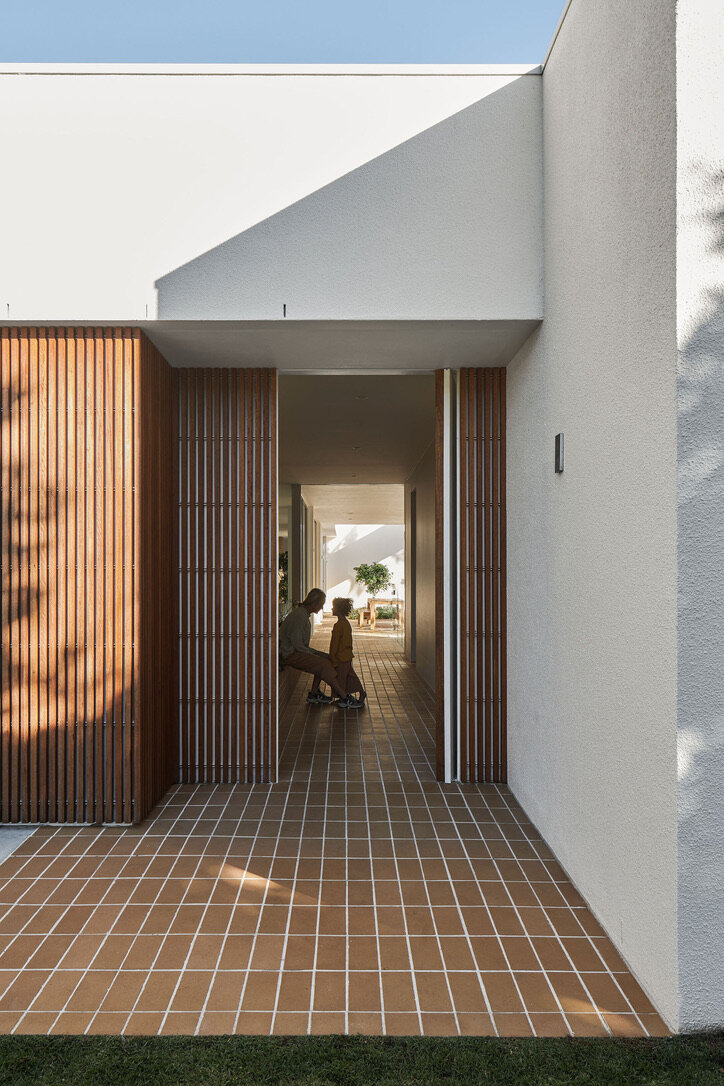 Modern architect designed house, white walls, vertical timber battens to front door, brick paving