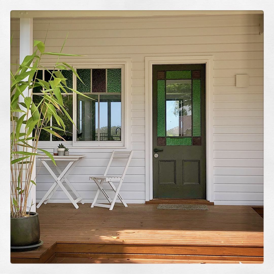 White weatherboard cottage coloured glass door and windows