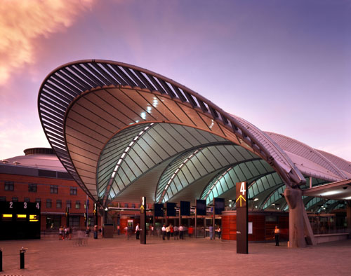Front entry of large public train station with curved steel and glass roof