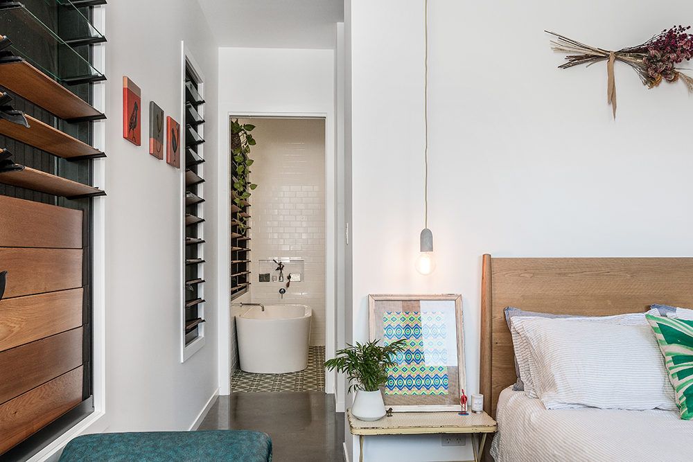 Modern architect designed home master bedroom with an ensuite with a freestanding bath. Timber louvred windows.