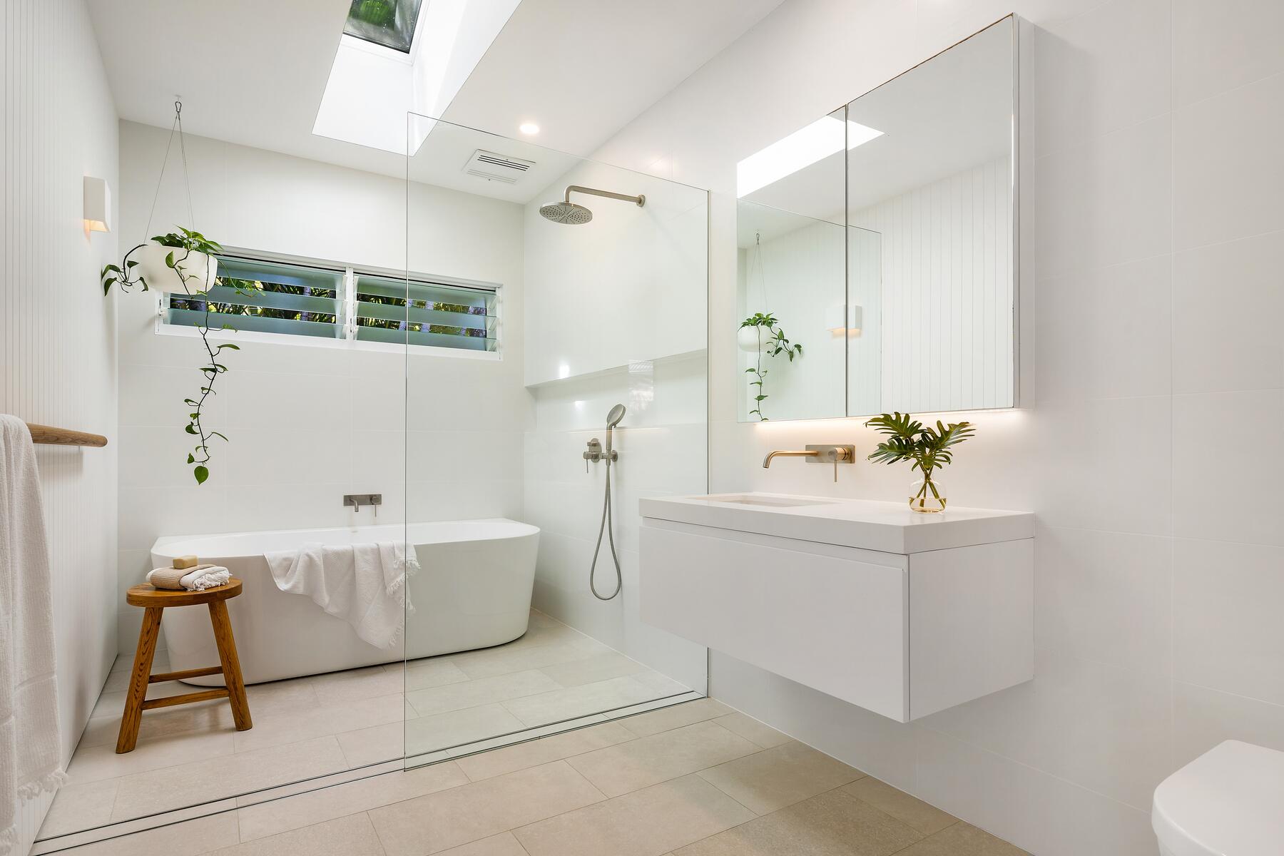 Modern architect designed bathroom with white wall tiles, cream porcelain floor tiles, back to wall bath