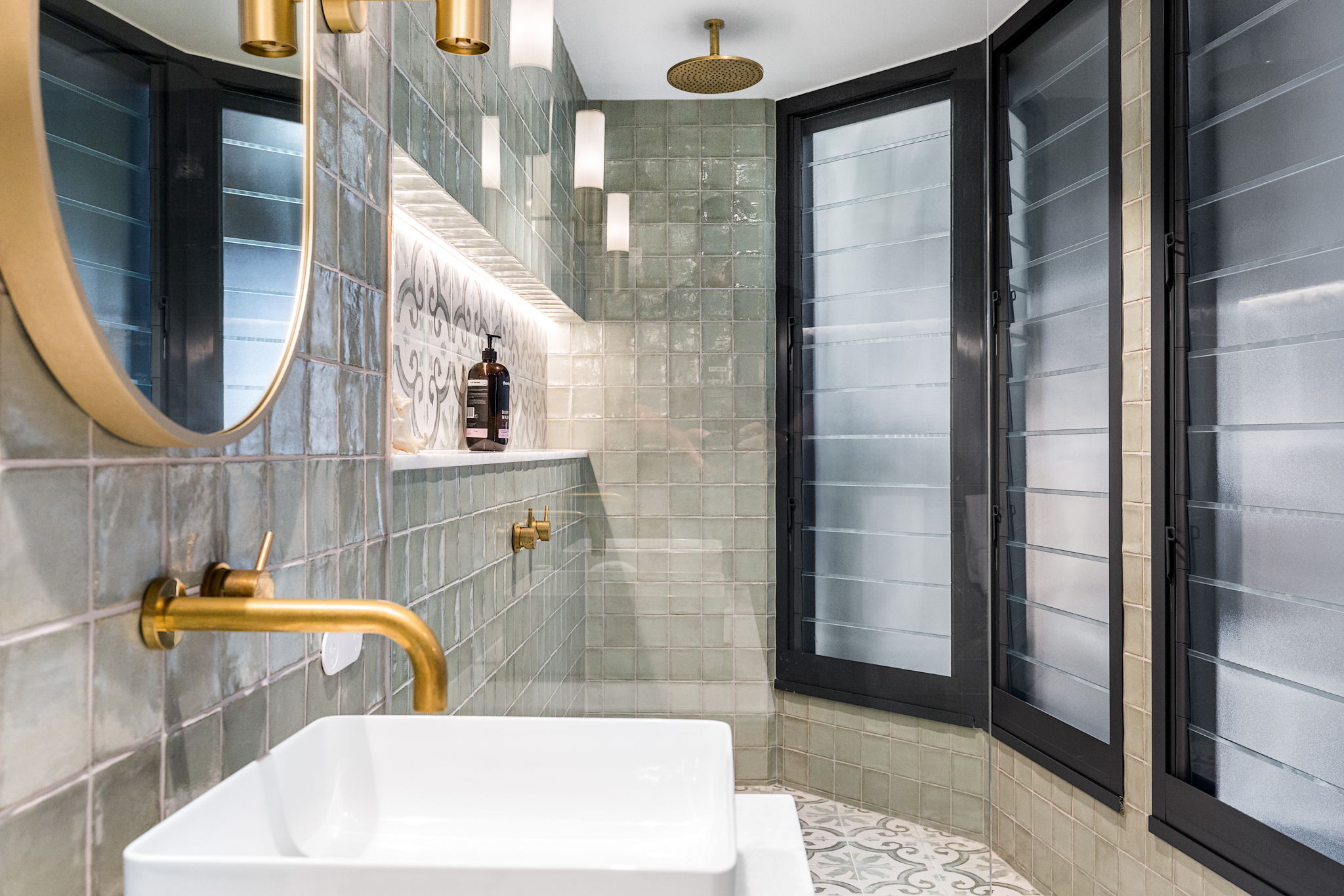 Aged brass tapware wiht gren tiles and shower niche