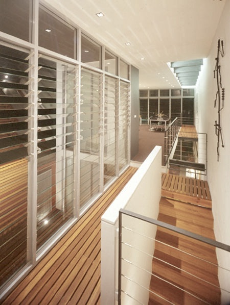 Modern architect designed house with open timber decking to wallkways, timber stair, steel & wire balustrades with glass louvre windows