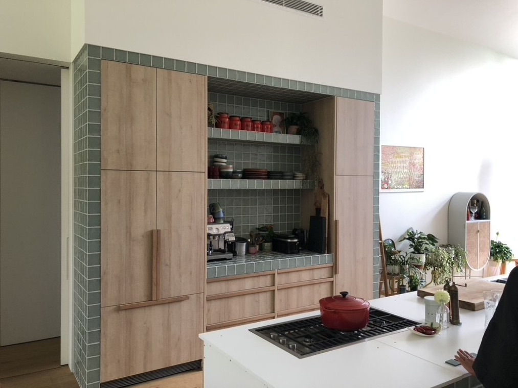 Modern architect designed kitchen with green tiled surround, timber look laminate cabinets