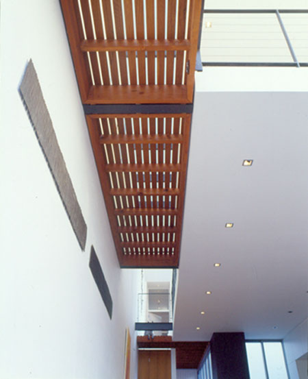 Modern architect designed house with open timber decking to walkway above.