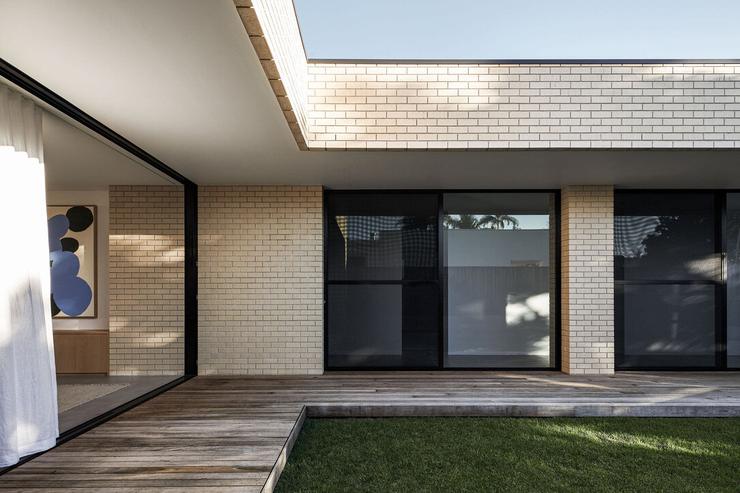 Modern architect designed house cream face brick walls, black aluminium framed sliding doors, timber decking