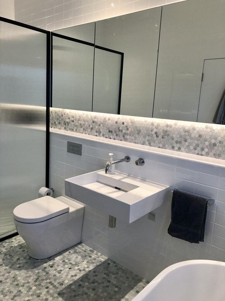Modern architect designed bathroom back to wall toilet, green marble mosaic tiles with glass vanity cupboards and wall hung basin