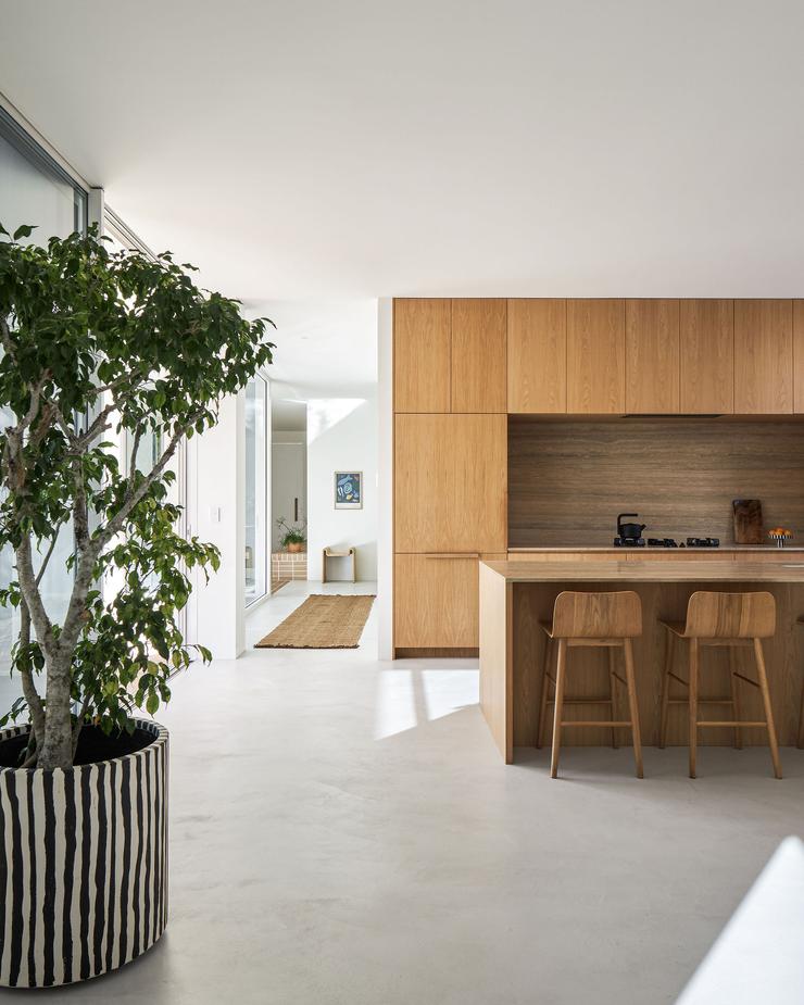 Modern architect designed kitchen with oak veneer cabinets, travertine benchtops, microcement floors