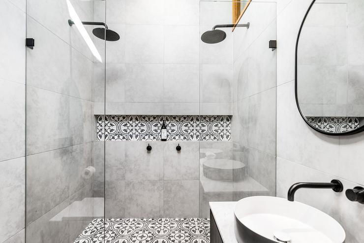 Modern architect designed bathroom with black tapware, patterened tile shower niche