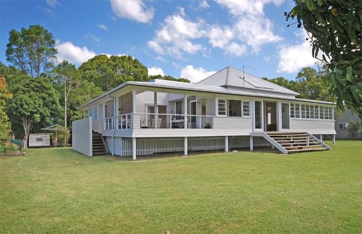White weatherboard Queenslander with stairs leading up to large sliding doors