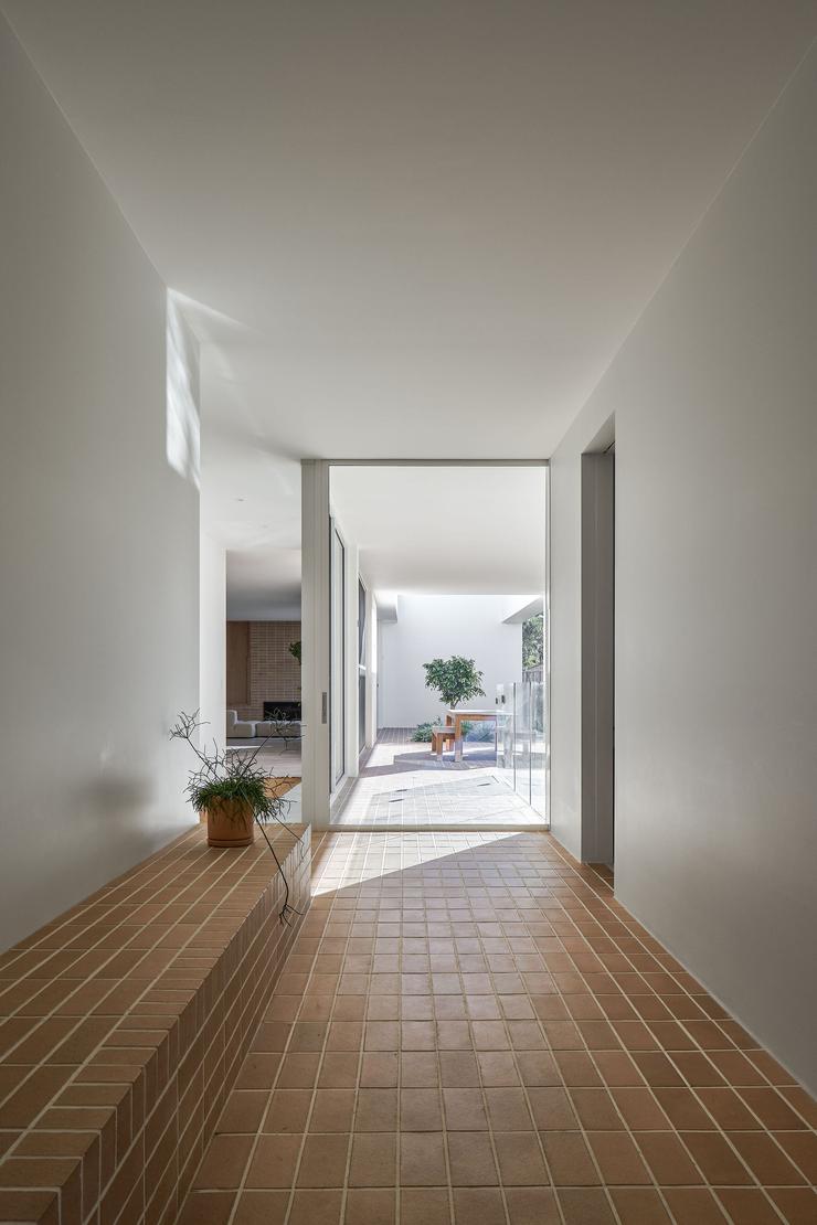 Modern architect designed entrance hallway, white walls, brick pavers on floor looking to outside courtyard