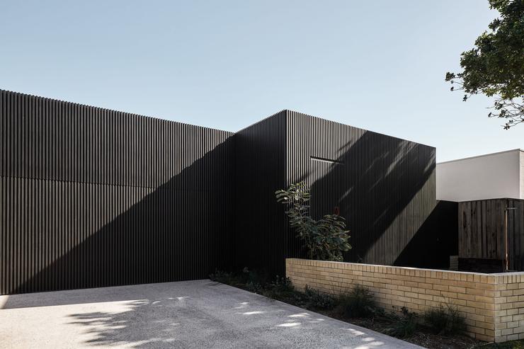 Modern architect designed house vertical black timber battened cladding, face brick low wall