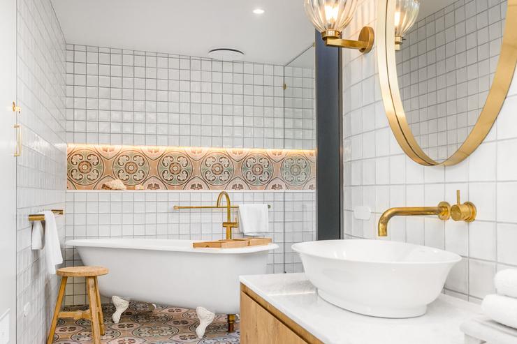 Bathroom renovation with timber vanity, stone benchtops, aged brass fittings and patterned tile shower niche